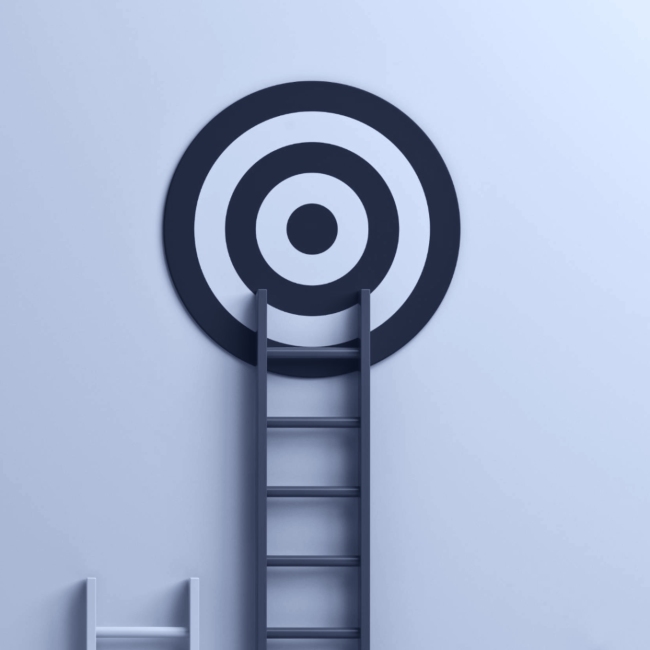 Gray ladder leaning against a wall with a black and white target symbol, representing goal achievement and progress