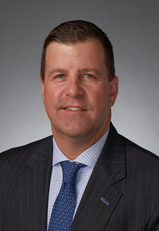 Blaine Ferguson, in a dark suit with a light blue shirt, is working as a Chief Operating Officer at Capital Wealth Advisors